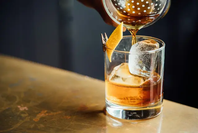 Drink som skjenkes i et glass i varmt lys