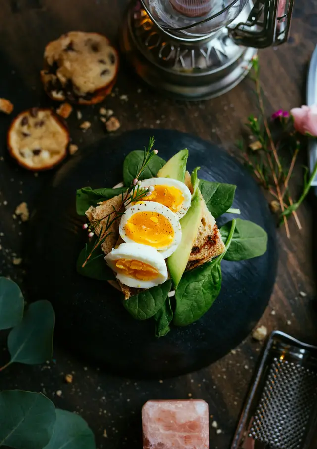 Brødskive med avokado og egg på mørk tallerken